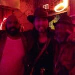 Three men posing for a photo in a bar.
