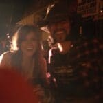 Smiling woman with man in plaid shirt.