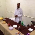 Man in striped shirt standing by a table with snacks.