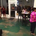 Four people stand in a cafe with a green floor.