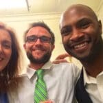 Three people smiling, one with a green tie.