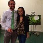 A couple posing in front of a painting.