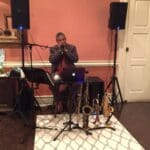Man playing saxophone with microphone and speakers.
