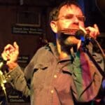 Man playing harmonica on stage.