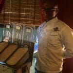 Man in a chef's uniform standing by a food cart.