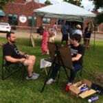 Two men sitting outside, painting and relaxing.