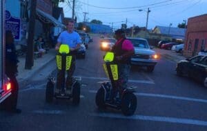 Two people riding police segways on street.