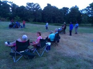 People sitting in chairs at a gathering.