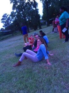 Group of friends sitting on grassy field.
