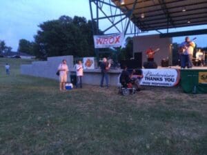 Outdoor stage with band and audience.