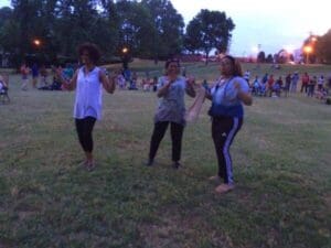 Three women smiling and dancing outdoors.