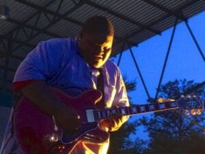 Man playing electric guitar on stage.