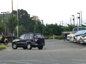 Black Jeep with many stickers parked in lot.