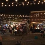 Night market with string lights and people.