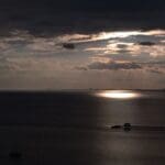 Pier and boat at sunset with cloudy sky.