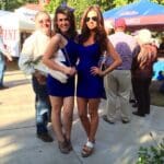 Two women in blue dresses and heels at a game.