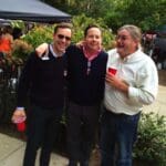 Three men smiling and holding red cups.