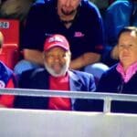 Three men sitting at a sporting event.