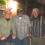 Three men stand outside a blues club.