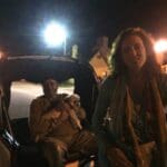Two people in a rickshaw with a dog.