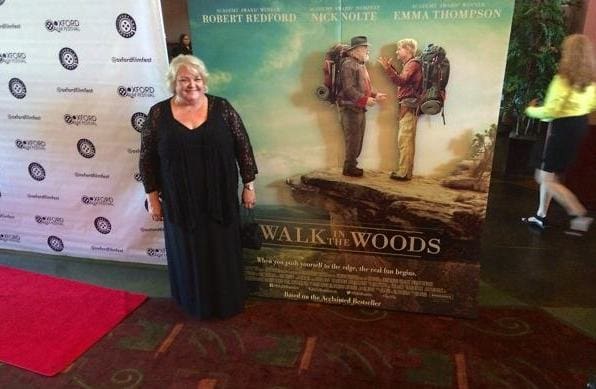 Woman standing next to movie poster