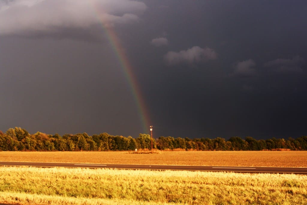 Rainbow over field and dark sky