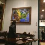 Man in hat looking at a map of the US.