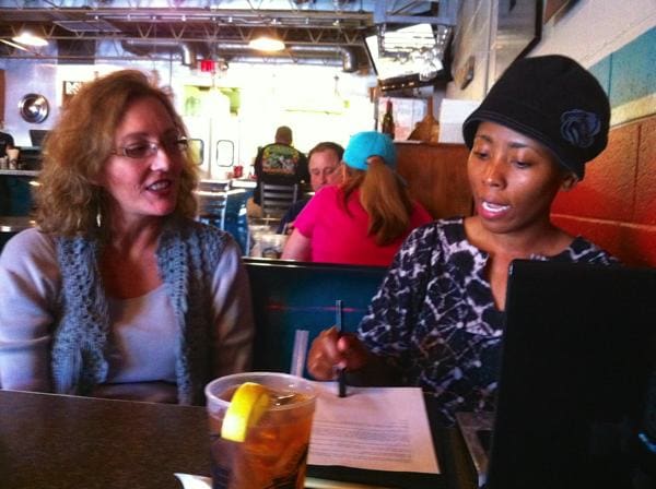 Casual meeting between two women at table.