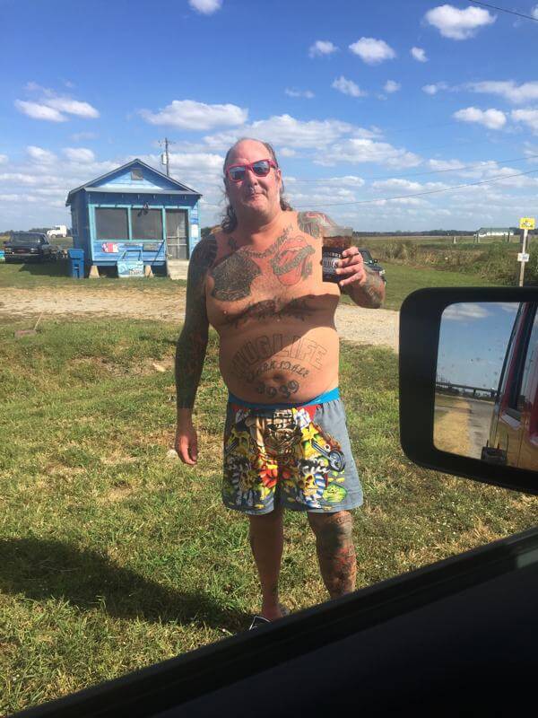 Smiling man in colorful shorts holding drink