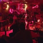 A woman playing guitar in a dimly lit bar.