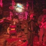 Band performing with red lights and a guitar.