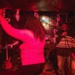 Woman singing with microphone and guitar player.