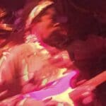 Person playing a purple electric guitar.