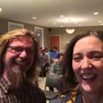 Two people smiling at a gathering.