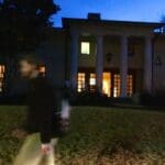Person walking in front of a fraternity house.