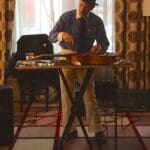 Man in hat playing a pedal steel guitar.