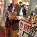 Man in a bookstore holding a magazine.