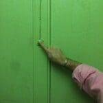 Hand reaching for a door buzzer.