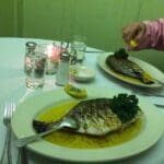 Two plates of grilled fish with lemon.