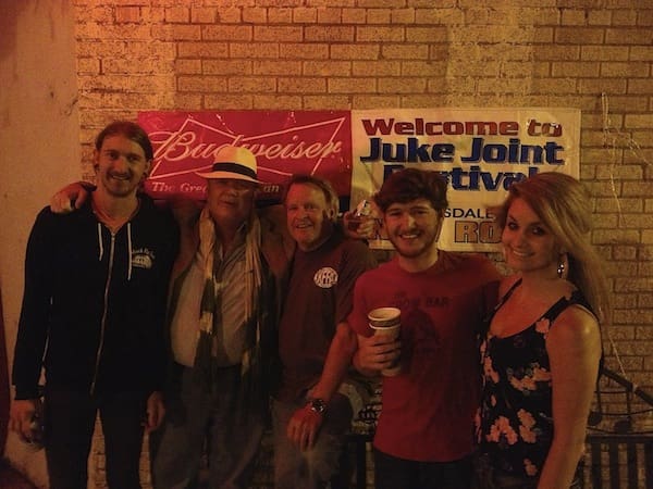 Group smiling in front of festival signs