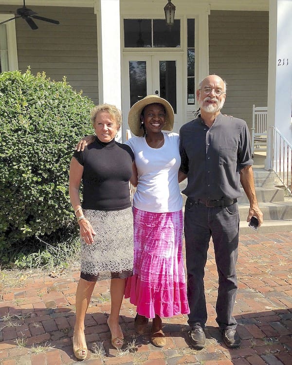 Three people posing outside a house