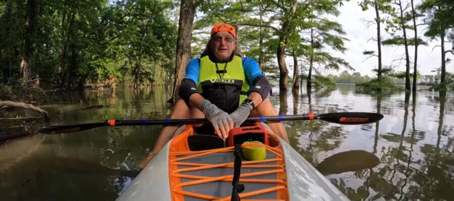 Man kayaking through forested waterway