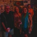 Three friends pose for a photo with drinks.