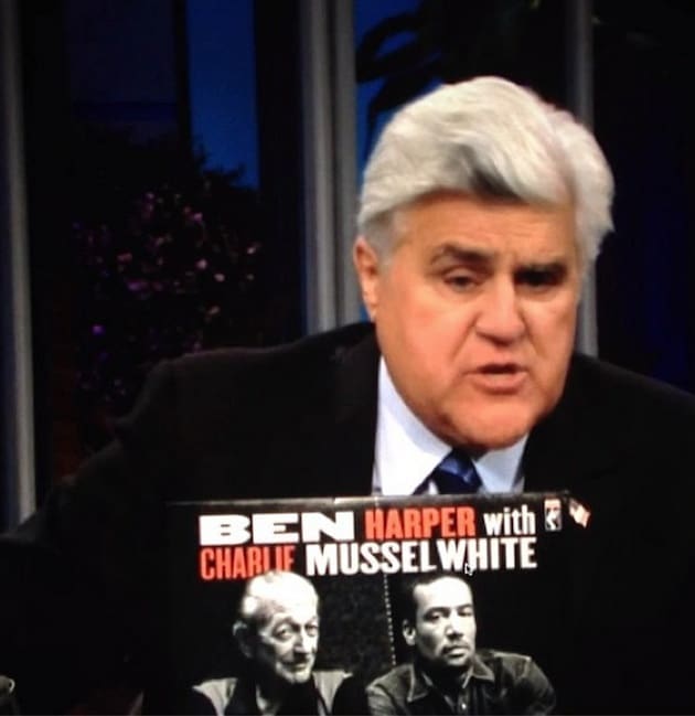 Gray-haired man displaying album cover