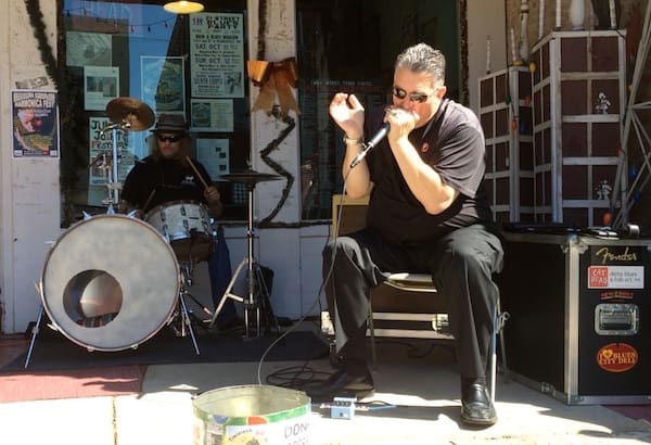 Musician playing harmonica outside shop