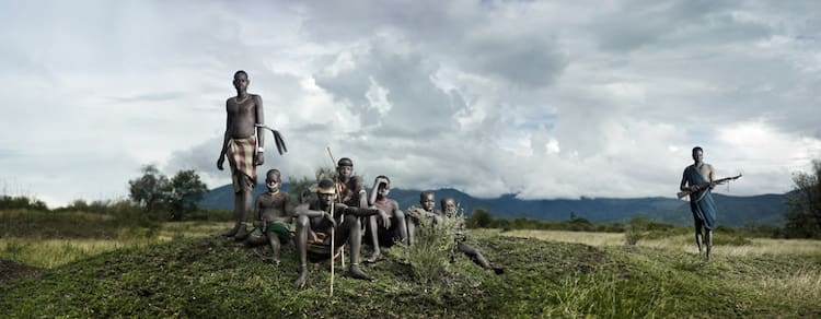 A woman of the Bodi tribe has fallen ill and died. The elder women of the village shout to the spirits and chant of her death to bring her soul to peace. The men perform a ceremonial procession and will guard the body of the deceased for 3 months. Bodi Me'en Tribe, Lower Omo Valley, Ethiopia. Photo by Joey L