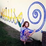 Man painting a mural with a blue spiral.