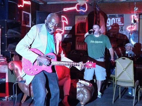 Elderly musician playing guitar on stage