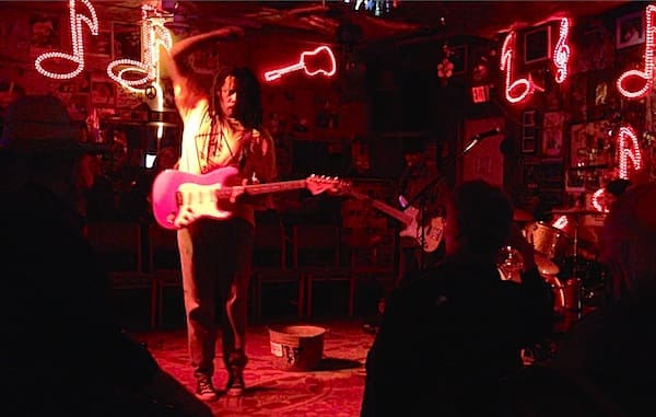 Guitarist performing in neon-lit bar