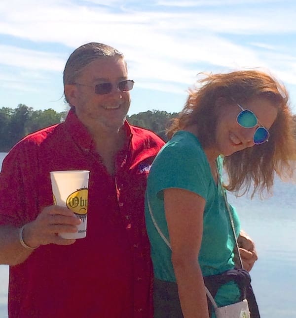 Smiling pair with drink by water